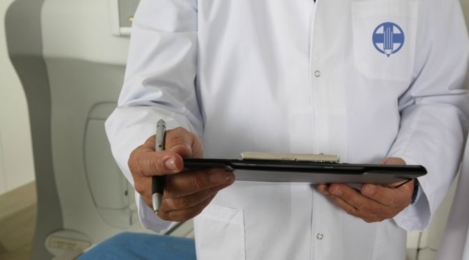 man in lab coat writing medical school admissions application